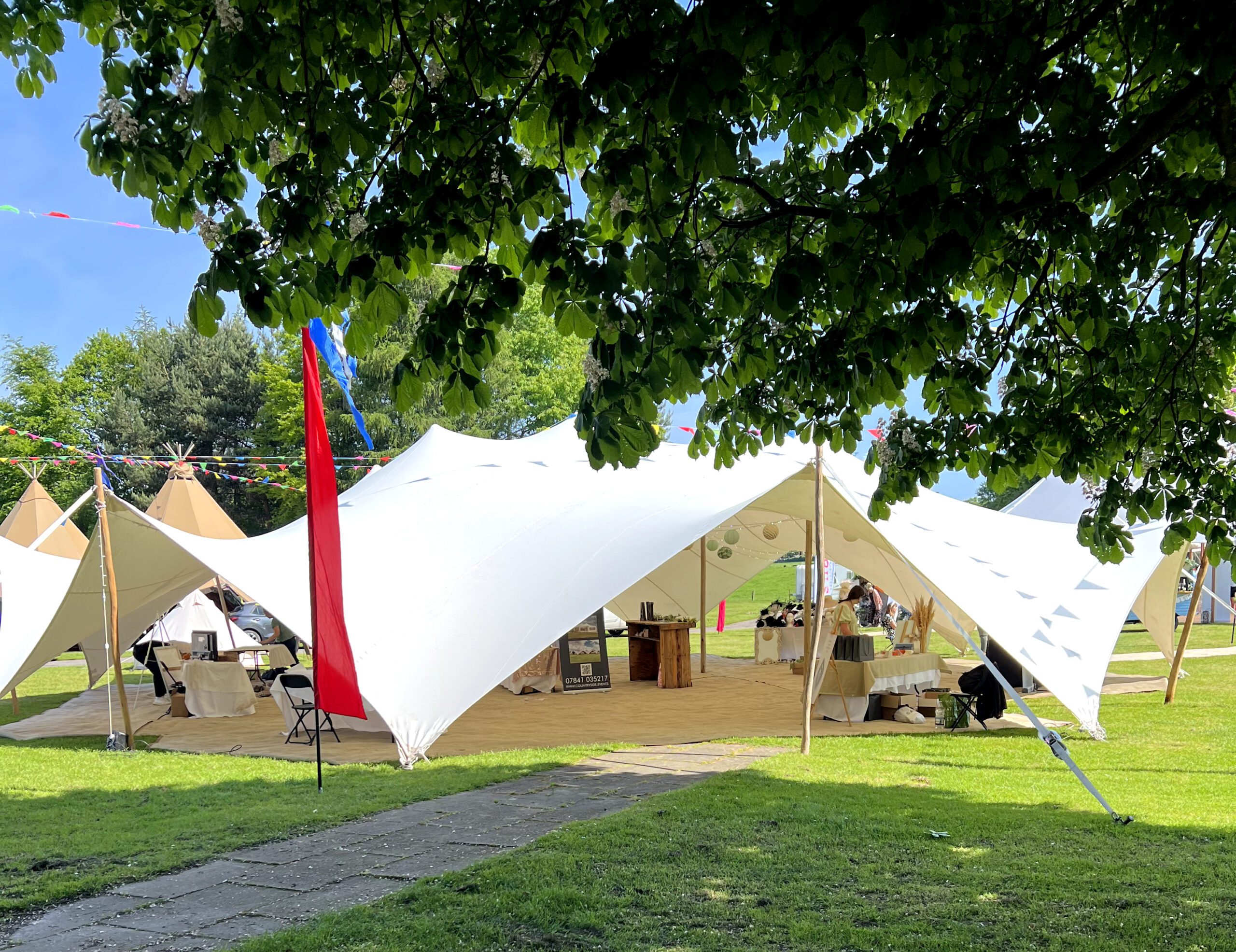 White stretch tent marquee with open sides amongst trees