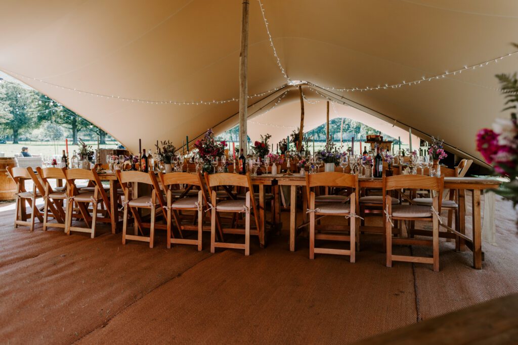 Stretch tent with rustic furniture for and flowers (photo by Gail Secker Photography)