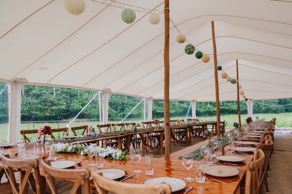 Rosebury 12x21m white stretch marquee interior with rustic dining furniture and green paper lanterns