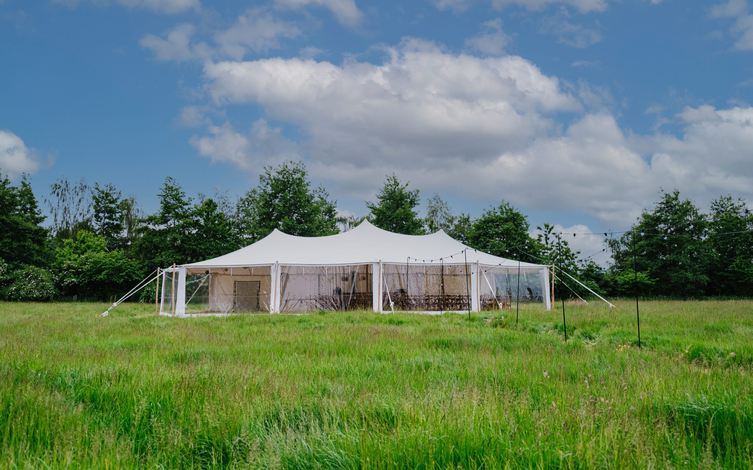 A white stretch marquee, pole tent style stretch tent in field