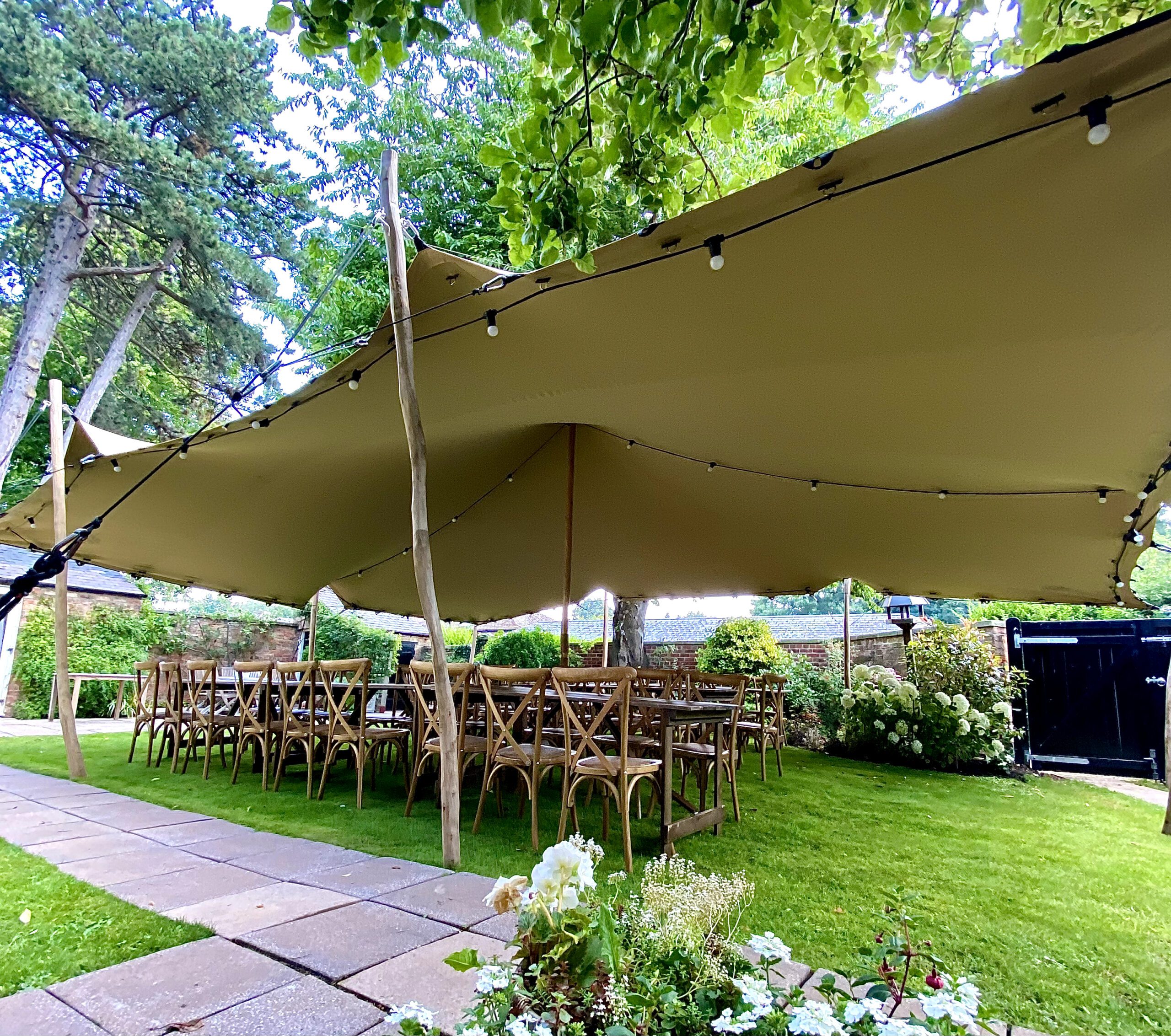 stretch tent in garden with rustic dining furniture