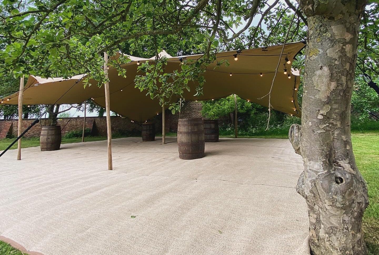 a stretch tent for drinks reception at Hornington Manor, with rustic barrels, festoon lighting and matting