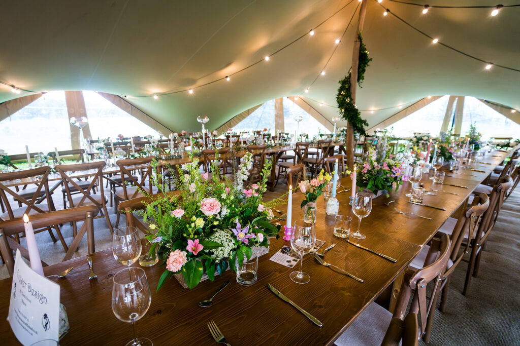 Chino colour stretch tent with windows, festoon lighting, candles, flowers and rustic dining furniture | Stretch Tent by Countryside Events (tent model: 'Ingleborough' 14x31m) | Photo by Kirsty Mattsson Photography | Florals by Flower Design, Ripon, North Yorkshire