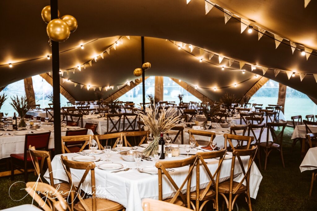 stretch tent with walls by Countryside Events with rustic furniture, cosy festoon lighting, bunting and neutral florals