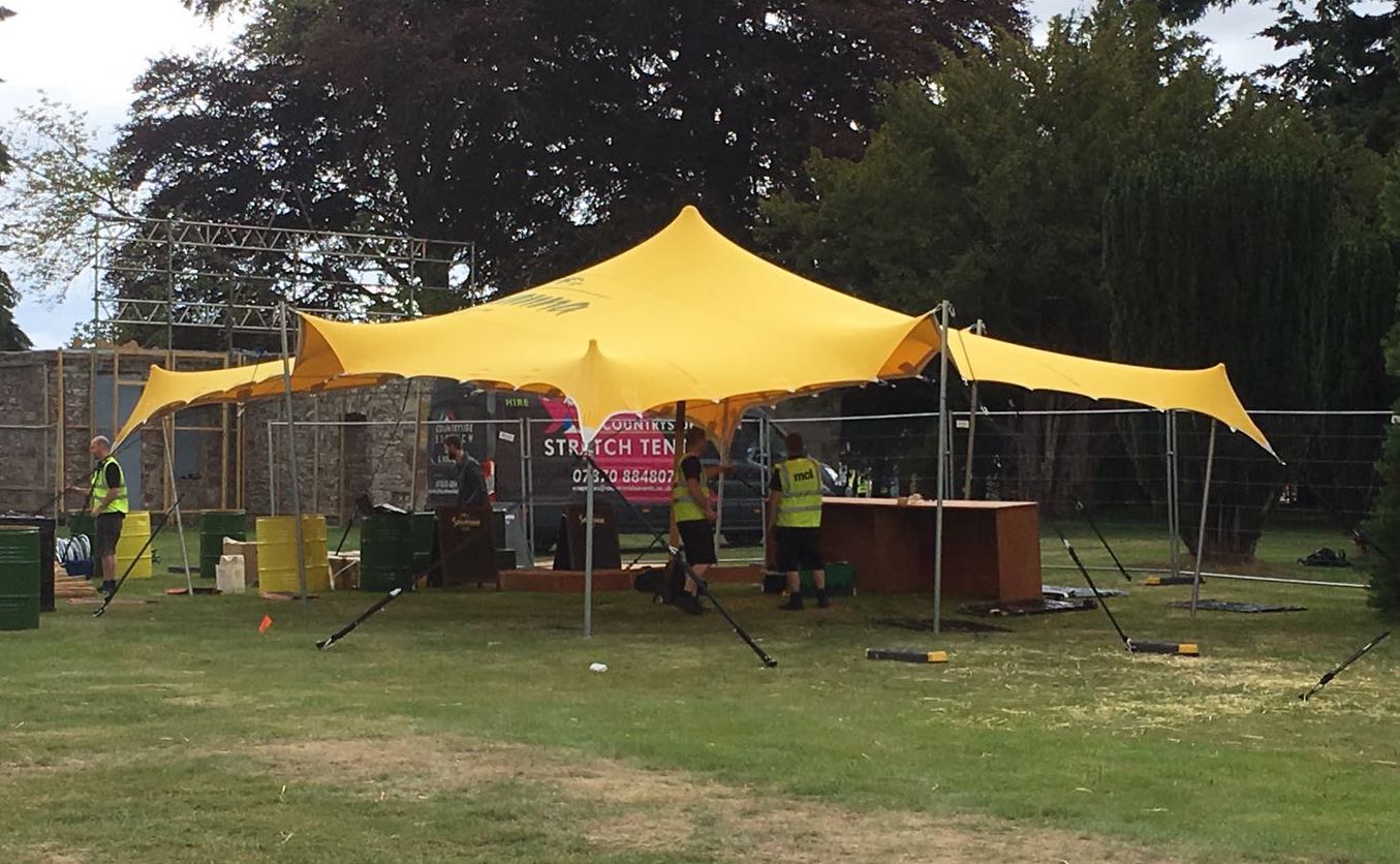 Yellow stretch tent by Countryside Events, in field, with staff rigging